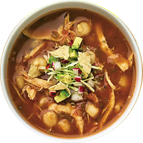 A bowl of chicken tortilla soup garnished with tortilla strips, served at a Mexican restaurant.